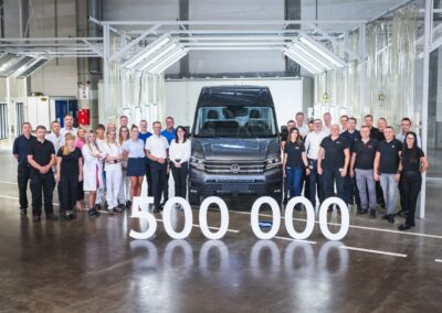 Mitarbeiter von Volkswagen stehen rechts und links eines VW Crafter.